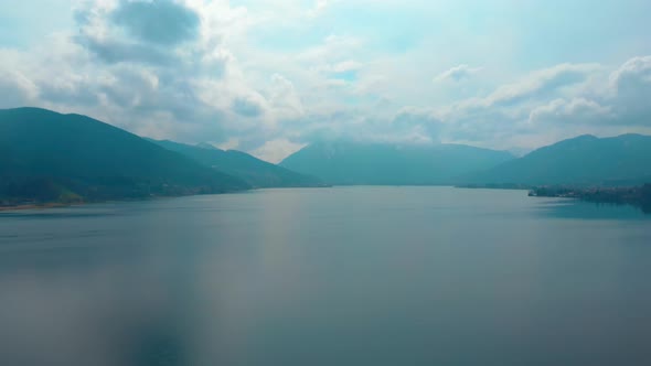 Descending aerial shot of the Tegernsee on a cloudy spring day. alt