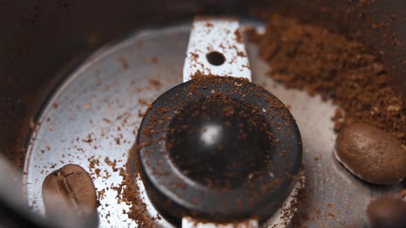 Coffee beans poured into electric grinder up close in slow motion alt