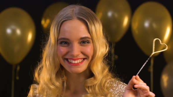 Smiling Blond Woman With Heart-Shaped Bengal Light Valentines Day Celebration alt