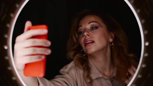 Beauty Blogger Female Holds Smartphone in Front of Ring Light and Takes Selfie