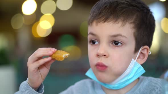 Preschooler Boy in Medical Mask Eats Chicken Nuggets From Fast Food Restaurant