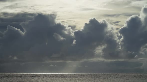 Dramatic clouds above the ocean, beautiful sunlight peaking through the clouds alt
