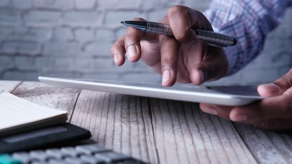 Man's Hand Working on Digital Tablet at Office Desk, Using Self Created Chart  alt