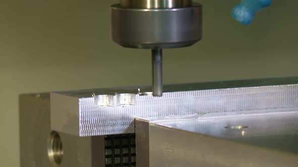 milling shapes out of a metal piece on a CNC machine alt
