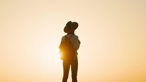 Traveling hiker with a backpack on the background of the bright sun alt