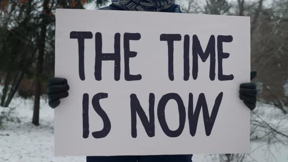 Demonstrating with the placard The Time is Now to fight the rapid climate change alt