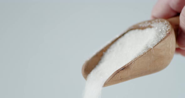 Sugar Is Poured From a Wooden Scoop alt