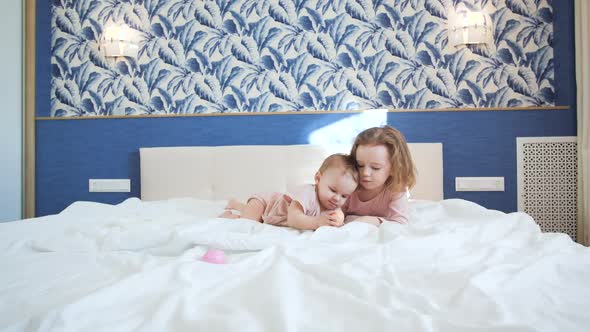 Two Sisters Play Early in the Morning in Bedroom on White King Size Bed alt