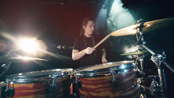 Male Drummer Playing Drums in Smoke. A Man with Dreadlocks Is Playing the Drum Set alt
