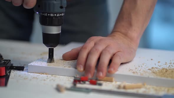 Man Making Hole in Board Using Drill