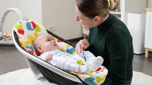 Portrait of Smiling Mother Sitting Next to Baby Son Rocking in Electric Rocker alt