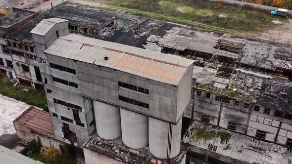 Old abandoned plant. Damaged buildings on the field. Broken windows and roof of a ruined factory.  alt