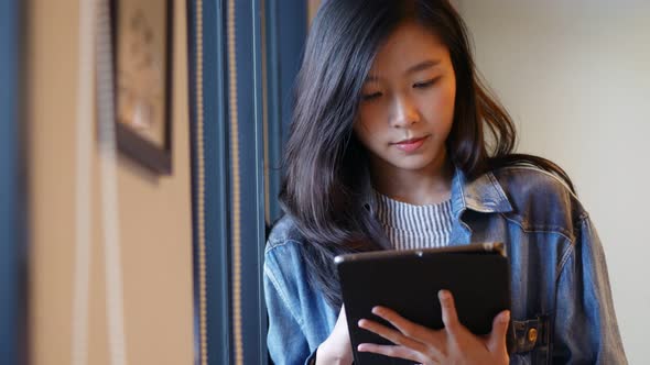 Young Asian woman using tablet beside a window at the office.