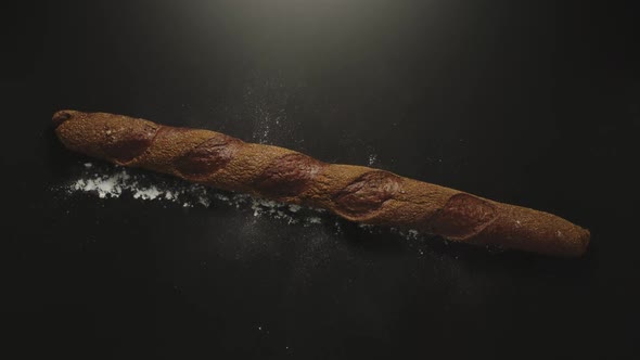 Brown Rye Baguette Falling Down On A Black Surface