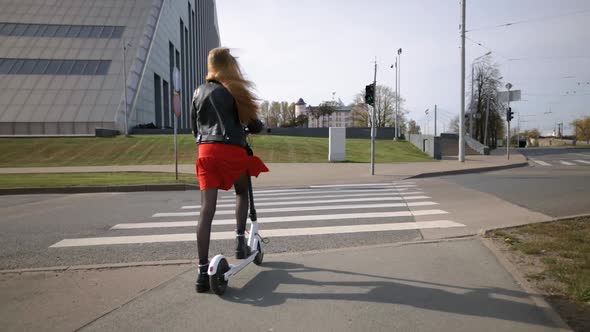 Yound Woman Crosses Road on Green Light Riding Electric Scooter alt