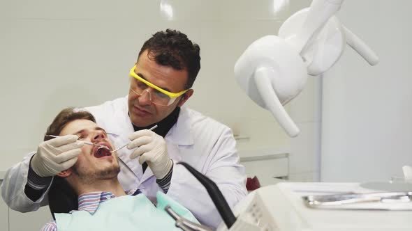 Professionl Mature Male Dentist Performing Dental Examination alt