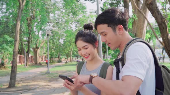 Young couple using mobile phone looking on map find landmark while spending holiday trip. alt