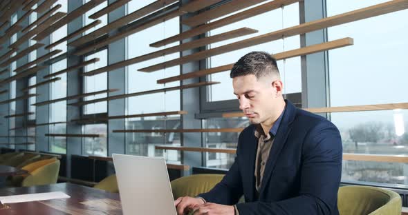 Concerned Man Working on Laptop Computer and Looking Away Thinking Solving Problem at Office alt