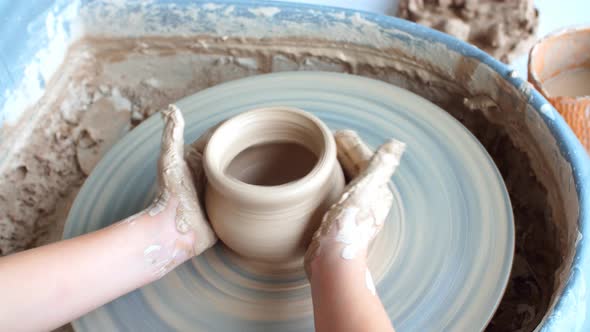 Happy Kid Is Pressing a Clay Vase on Wheel, Kid Is Working at Pottery Wheel Slowly and Molding a