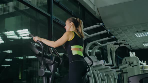 Fit Athletic Woman Exercising on an Elliptical Machine