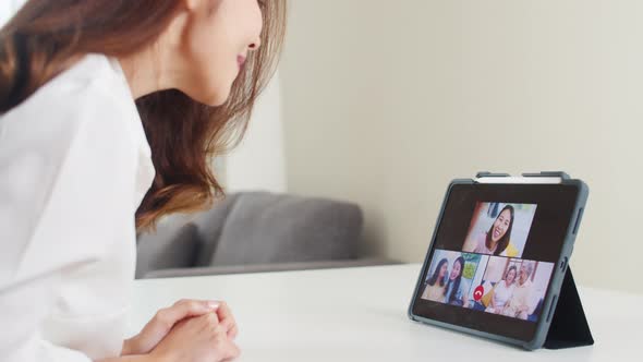 Young Asian business female using tablet video call talking with family while working alt