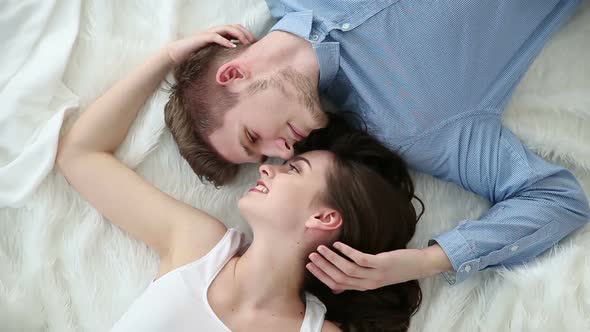 Young Loving Couple Lying on Bed at Home