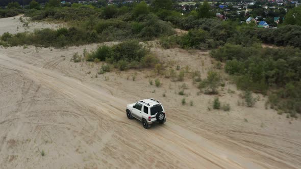 Aerial View of a Car Driving on Sand alt