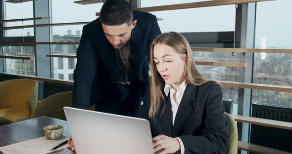 Portrait of a Man and a Woman Discussing Work with Notebook in the Brightly Lit Modern Office alt