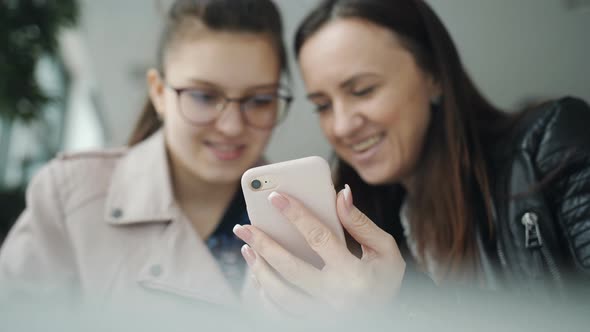 Mother and Daughter a Teenager Look to the Smartphone alt