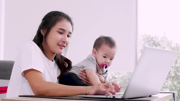 Happy mother with baby and working with laptop, Happy family at home mommy baby