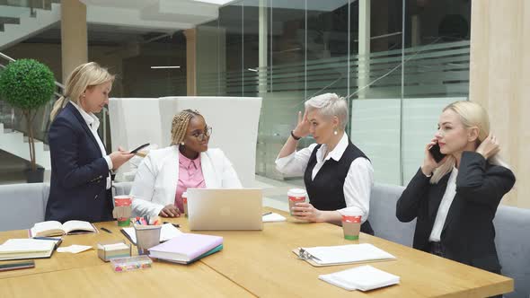Group of Business Women Talking While Sitting at Table Use Laptop
