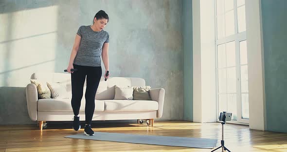 Sportive Woman with Dumbbell Bars Comes to Mobile Phone alt