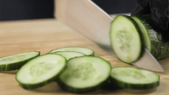 Cook Chef in Gloves Cutting the Cucumbers Into Slices Closeup View