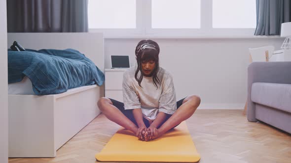 Young Woman Stretching in Her Bedroom alt