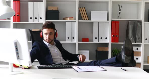 Businessman in Headphones Working with Legs on Table