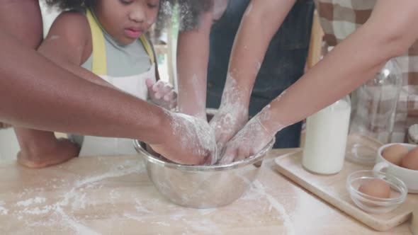 Close up of African American family with little adorable daughters thresh dough  together