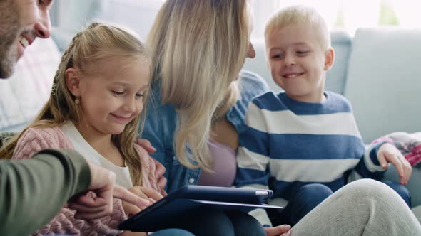 Happy family using a tablet in living room alt