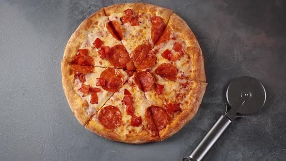 Round pizza with pepperoni and mozzarella cheese and knife rotating