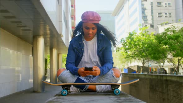 Female dancer with skateboard using mobile phone in the city 4k alt