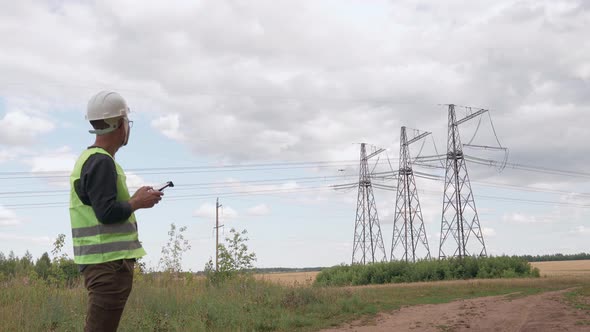 An Electrical Engineer Forcing a Drone To Inspect High Voltage Poles Before Starting a Project alt