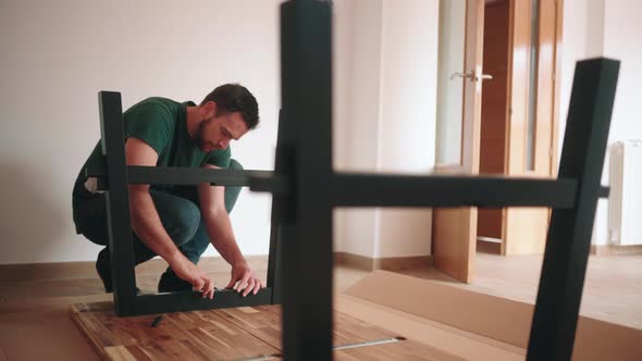Man Fastening Bolts Of DIY Table Using An Allen Wrench In The House. static alt