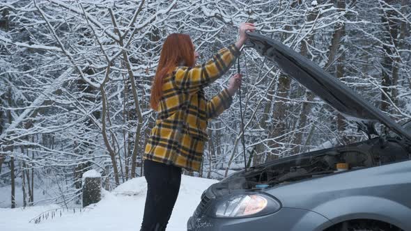 A Young Woman Opens the Hood Car