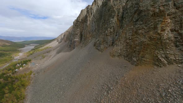 FPV Sports Drone Shot Flight Near Cracked Rock Formation Textured Mountain Valley with House alt