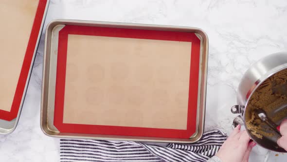 Flat lay. Step by step. Scooping peanut butter cookies dough with dough scooper into the baking shee alt