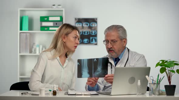 Senior Doctor Consults Patient By Showing Her Picture of Leg and Discusses Treatment of Disease alt