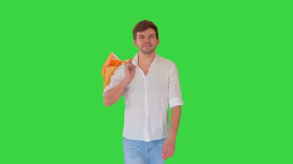 Handsome Man in Casual Clothes Walking with Shopping Bags Looking at Camera on a Green Screen alt