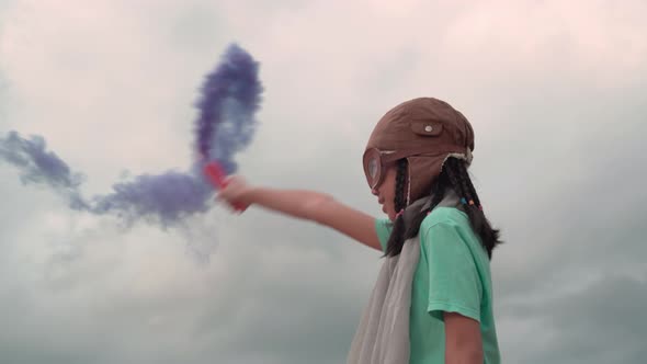 Asian kid playing at outdoor with color smoke, Young girl with pilot goggles and hat