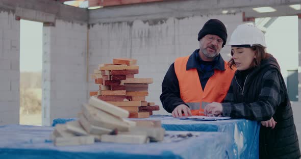 Concentrated Engineers Discussing Examining and Developing at Construction Site alt