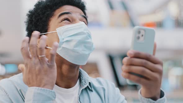 Portrait African American Man Guy Wearing Medical Mask with Phone Wins Online Bonus Mobile Game Gets alt