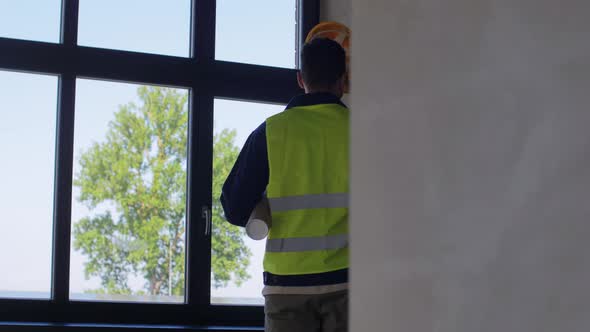 Builder in Safety West with Blueprint at Window